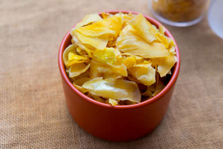 Close up of a pile of dried jackfruit chips in orange bowl