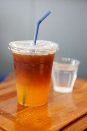 Closeup image of a glass of orange cold brew coffee on wooden tableの写真素材
