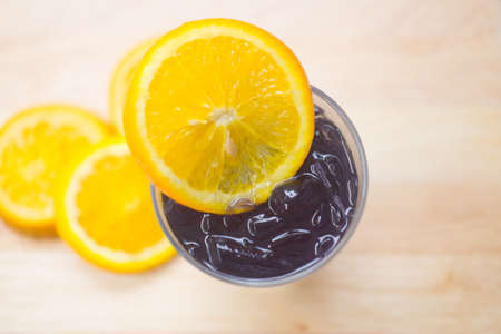 Black charcoal cold drink with orange slice in glassの写真素材