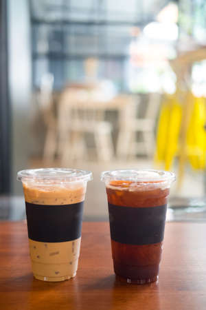 Cup of iced black coffee americano and iced coffee latte on wooden at a hot dayの写真素材