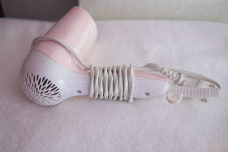 Pink and white hair dryer on white towel in hotel