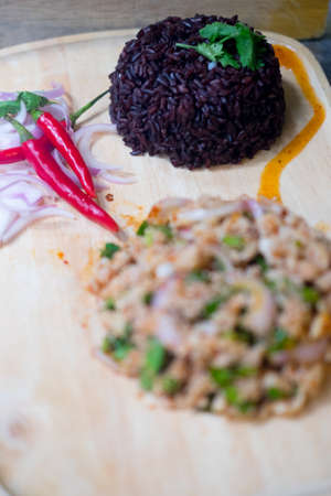 Thai style chicken salad served with rice berry in waiter handの写真素材