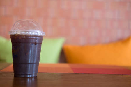 Cold black coffee with ice on wood table in coffee shop