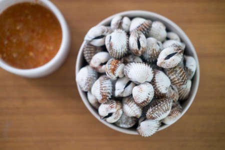 Cockles with chili dip on wooden table. It is a delicacy among Asiansの写真素材