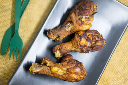 Fried chicken drumsticks on black dish. Selective focus