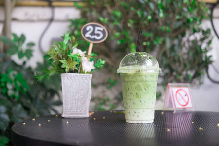 Ice milk green tea in plastic glass on black wood table in coffee shopの写真素材