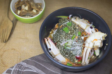 Fresh raw blue crab in spicy sauce in black bowl