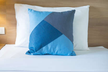 Blue and white pillows on sheets bed. Vacation concept with apartment interior.