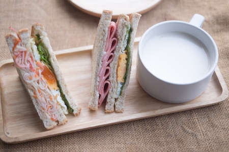 Triangle sandwich with whole wheat bread and cup of hot milkの写真素材