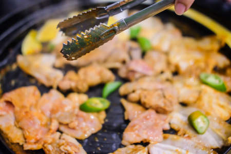 Tongs catch grill pork bbq in korea style (close up)