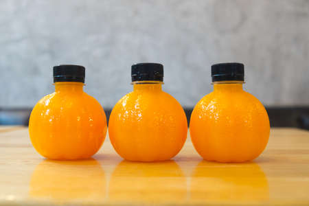 Three plastic bottle of orange juice put on wooden tableの写真素材