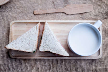 Simple sandwich whole grain bread with fresh milk on wooden trayの写真素材