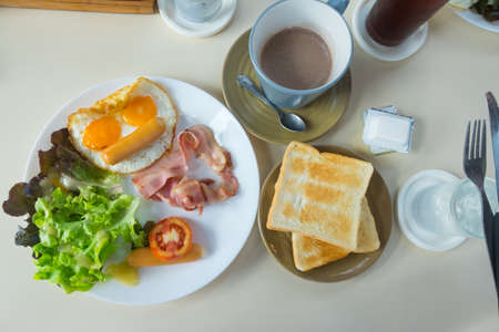 Homemade breakfast with fried egg toast sausage vegetable jam and hot coffee in top view