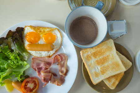 Homemade breakfast with fried egg toast sausage vegetable jam and hot coffee in top view