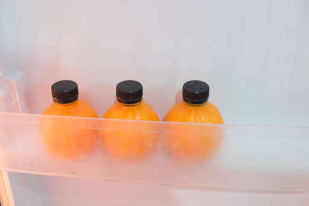 Plastic bottles of fresh orange juice in fridgeの写真素材
