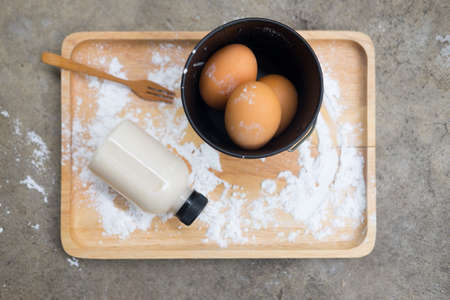 Ingredients for baking: flour, eggs and milk on a wooden trayの写真素材