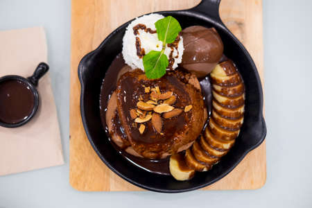 Hot chocolate lava cake with chocolate ice cream ball, slice banana and whipped cream served on panの写真素材