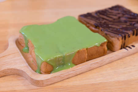 Bread with green steamed pandan custard on top put on wooden tray