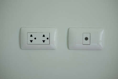 A white home electrical outlet on a light grey wall.