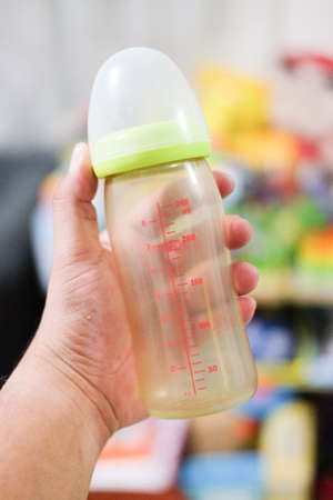 Clear baby bottle with rubber nipple in hand