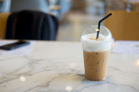 A cup of ice cappuccino in coffee shop on table.の写真素材
