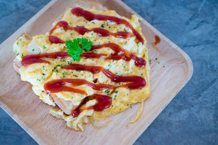 Scrambled eggs with ketchup on toasted bread put in wooden dish