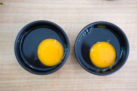 Fresh raw egg in black bowl (two egg)