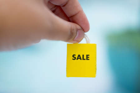 Closeup of the hand of a young caucasian man holding a paper shopping bag. Sale promotion season conceptの写真素材