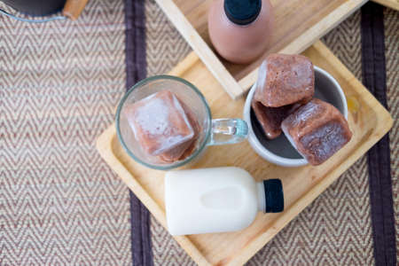 Chocolate ice cubes with bottle of milk on wood trayの写真素材
