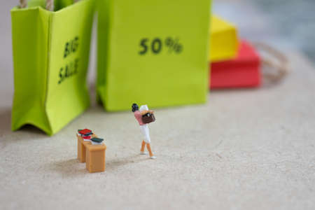Women looking for shopping she work hard for relex to shopping. Concept of business for planning promotion in mid year (Miniature people)の写真素材