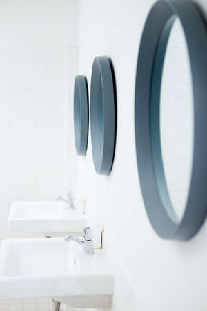 white sinks and mirror on the wall at public placeの写真素材