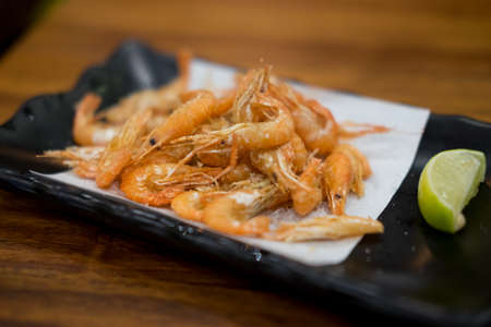 Fried mini shrimp (deep-fried) with lemon on black dishの写真素材
