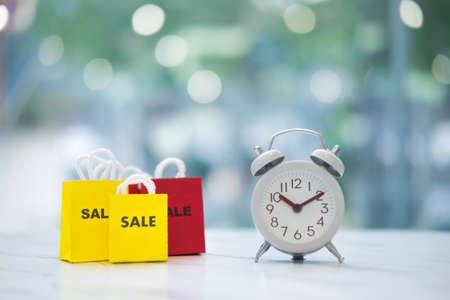 White vintage alarm clock and paper shopping bag. Business finance shopping concept wake up time.の写真素材