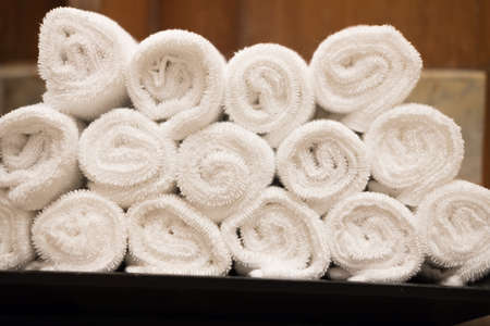 Rolls of white cotton towel in bedroom. Concept of care cleanliness health and spa treatments.の写真素材