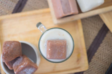 Frozen chocolate into a cube melting away in a glass with milk making a homemade delicious summer drinkの写真素材
