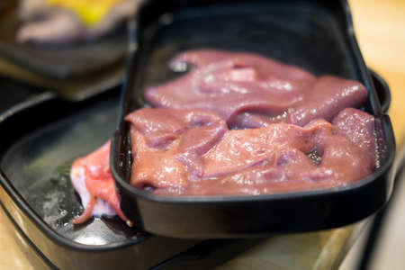 Pork raw liver on black tray ready to cookの写真素材
