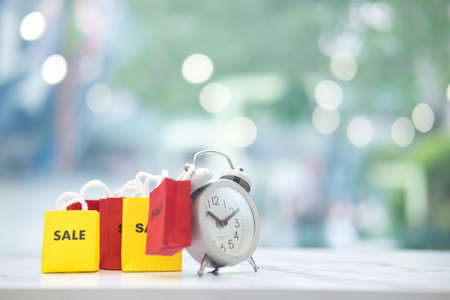 Time for shopping concept. Shopping bag hang on alarm clockの写真素材