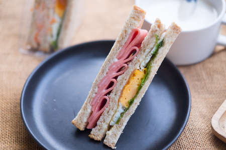 Fresh sandwich with ham and egg served on black dishの写真素材