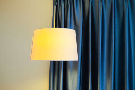 Modern lamp with blue curtain. Warm orange lightの写真素材