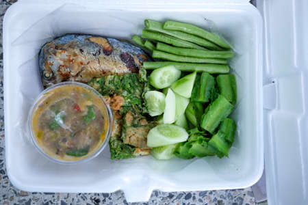 Mackerel fish chili spicy sauce with boiled vegetables put in foam box