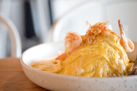 Rice and scrambled egg with shrimp in a white plateの写真素材