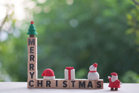 A tall tower of wooden blocks Merry Christmas with toy ornament (Snowman, Gift box, Santa claus, Christmas tree and cap santa)の写真素材