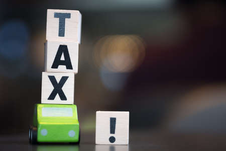 Miniature wooden green car and wooden cubes with word TAX. Car tax conceptの写真素材