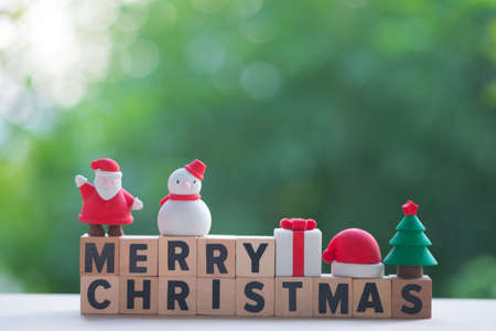 Merry Christmas wooden blocks with toy for decoration. Concept of Christmas holiday festive theme and empty space for your text (Snowman, Gift box, Santa claus, Christmas tree and cap santa)の写真素材