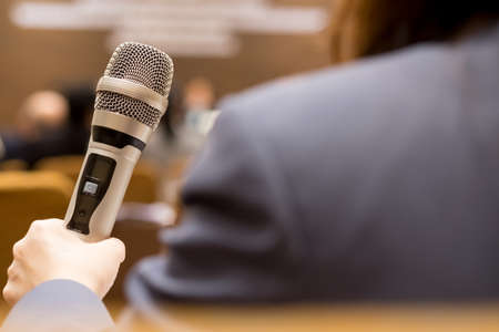 Hands business people holding microphones for speech or speaking in seminar room, talking for lecture to audience university, Event light convention hall Background. Seminar conference conceptの写真素材