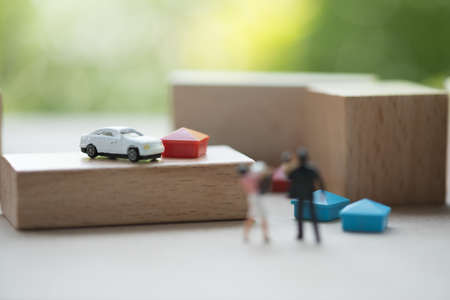 Happy success marriage love life concept, miniature lovely couple husband carrying his infant and wife with car and house. Can use in mortgage and property investment.の写真素材