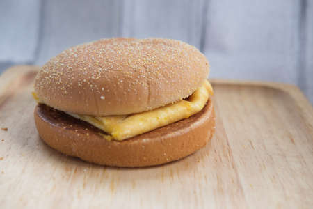 Egg and cheese breakfast sandwich with english muffin served on wooden tray