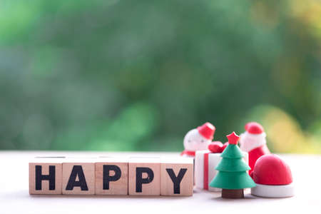 Christmas tree beside wooden block with "HAPPY" and nature background. Copy space for text or content. Concept happyの写真素材