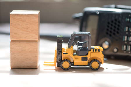 Toy forklift truck and wooden block with radio communication background. Concept of international freight transportの写真素材