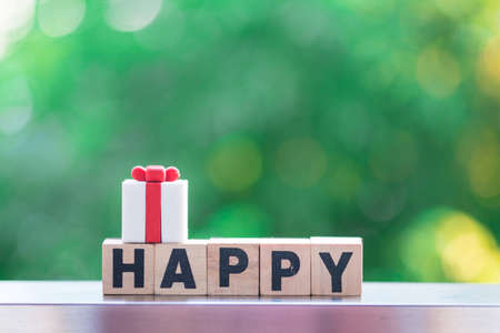 Wooden block with "HAPPY" text with gift box on top, for you can  design for greeting cardsの写真素材